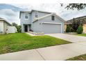 Charming two-story home with a gray roof, attached garage and green front lawn at 11926 Grand Kempston Dr, Gibsonton, FL 33534