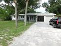 Single story home with an attached garage, a car in the driveway, and mature trees at 12417 N Rome Ave, Tampa, FL 33612