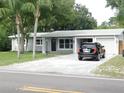 Well-kept single-story house with an attached two-car garage, palm trees, and a car in the driveway at 12417 N Rome Ave, Tampa, FL 33612