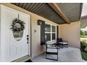 Detailed view of a white front door with wreath, exterior lights, and a cozy seating area on the porch at 1800 Mapleleaf Blvd, Oldsmar, FL 34677