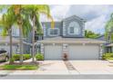 Charming townhome showcasing curb appeal with palm trees and a two-car garage at 18136 Nassau Point Dr, Tampa, FL 33647