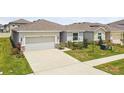 Attractive single-story home showcasing a two-car garage, stone details, and a green lawn on a sunny day at 2518 Chapel Oak Bnd, Wesley Chapel, FL 33543