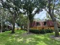 Exterior view of townhome with red tile roof, green grass and many trees at 2716 11Th Ct, Palm Harbor, FL 34684