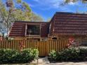 Inviting townhome featuring a red tile roof, fenced entry, and landscaped greenery at 2716 11Th Ct, Palm Harbor, FL 34684