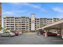 The exterior of a multi-story condo building features covered parking, well-maintained landscaping and a lovely facade at 450 Treasure Isle Causeway # 212, Treasure Island, FL 33706