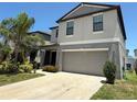 Two-story home with a grey exterior, a two-car garage, a front entrance with columns, and manicured landscaping at 10221 Carloway Hills Dr, Wimauma, FL 33598