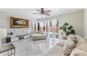 Bright living room with white tile flooring, ceiling fan, and sliding glass doors to the backyard at 10520 Winrock Pl, Tampa, FL 33624