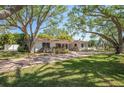 Beautiful single-story home with lush landscaping, mature trees, and a brick paved driveway at 1100 Snell Isle Ne Blvd, St Petersburg, FL 33704