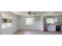 Spacious living room with white walls, several windows, and direct access to the kitchen at 12113 Victory Dr, Hudson, FL 34667