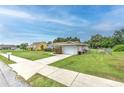 Well-kept home with a spacious driveway, attached garage, and grassy yard on a sunny day at 13311 Omega Ct, Dade City, FL 33525