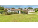 Inviting single-story home with lush green lawn, a blue front door, and manicured bushes at 13311 Omega Ct, Dade City, FL 33525