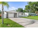 Charming single-story home featuring a manicured lawn, long driveway, and a black and white color scheme at 4741 76Th N Ave, Pinellas Park, FL 33781