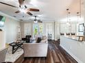 Bright and airy living room with wood floors, modern furnishings, ceiling fans, and natural light from shuttered french doors at 539 Treviso Dr, Apollo Beach, FL 33572