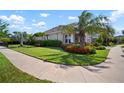 Well-maintained front yard with lush green grass, mature trees, and colorful flowerbeds surrounding a single-Gathering home at 7520 Paradiso Dr, Apollo Beach, FL 33572