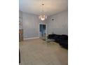 Open-concept living room with neutral tile floors and decorative chandelier at 8718 Lindenhurst Pl, Tampa, FL 33634