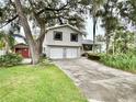 Charming two-story home with a two-car garage and mature landscaping creating a welcoming curb appeal at 945 College Hill Dr, Clearwater, FL 33765