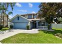 Charming two-story home featuring blue exterior, well-manicured lawn, and a two-car garage at 1032 Jacob Way, Odessa, FL 33556