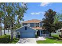 Charming two-story blue home featuring a well-manicured front lawn and a cozy front porch at 1032 Jacob Way, Odessa, FL 33556