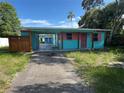 A colorful one-story home with a covered carport with unkempt front lawn at 1504 Stevensons Dr, Clearwater, FL 33755