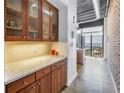 Modern kitchen featuring wood cabinetry, granite countertops, brick wall, and an industrial-style ceiling at 175 2Nd St S # P-2, St Petersburg, FL 33701