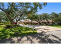 Well-manicured lawn with mature trees and a circular driveway leading to a spacious single-story home at 1835 Alicia Way, Clearwater, FL 33764