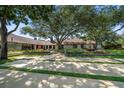 Beautifully landscaped front yard with mature trees and manicured gardens accenting a single-story home at 1835 Alicia Way, Clearwater, FL 33764