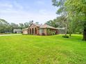 Charming single-story home with a screened-in pool, lush greenery and spacious front lawn at 2409 Heather Manor Ln, Lutz, FL 33549
