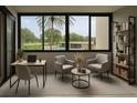 Bright interior living area with desk, seating, and a view of the pool and palm trees outside at 2621 Cove Cay Dr # 206, Clearwater, FL 33760
