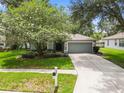 Inviting single-story home with mature tree, lush landscaping, and gray exterior paint at 2910 Red Coat Cir, Brandon, FL 33511