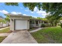 Charming home featuring a well-manicured lawn, a driveway, an attached garage, and lovely landscaping at 4321 S Thatcher Ave, Tampa, FL 33611