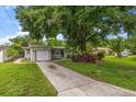 Charming home featuring a well-manicured lawn, a driveway, an attached garage, and lovely landscaping at 4321 S Thatcher Ave, Tampa, FL 33611