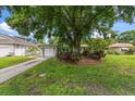 Charming home featuring a well-manicured lawn, a driveway, an attached garage, and lovely landscaping at 4321 S Thatcher Ave, Tampa, FL 33611