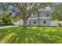 Charming single-story home featuring a well-manicured lawn and a blue front door under the shade of a mature tree at 4717 W Anita Blvd, Tampa, FL 33611