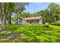 View of the house with a metal roof, manicured lawn, and mature trees providing shade at 8600 Shenandoah Run, Wesley Chapel, FL 33544
