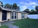 Tan colored home with large windows and a green lawn with a black front door at 10102 Missy Ct, Tampa, FL 33615