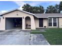 Beige single Gathering home featuring an attached garage, and lawn with mature landscaping at 10102 Missy Ct, Tampa, FL 33615