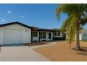 Inviting single-story home with palm tree, neutral exterior, attached garage and gravel yard at 10914 Oakdale Ave, Port Richey, FL 34668
