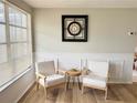 Bright living room featuring wood floors, large window, two chairs, and an open view to the dining area at 10914 Oakdale Ave, Port Richey, FL 34668
