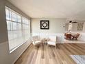 Bright living room featuring wood floors, large window, two chairs, and an open view to the dining area at 10914 Oakdale Ave, Port Richey, FL 34668