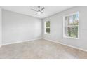 Neutral bedroom with tile flooring, ceiling fan, and two bright, screened windows at 13334 Palmera Vista Dr, Riverview, FL 33579