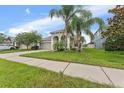 Single Gathering home featuring an attached garage, palm trees, and a concrete sidewalk at 13334 Palmera Vista Dr, Riverview, FL 33579