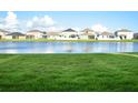 Scenic backyard view with a tranquil lake, surrounded by lush green grass and neighboring houses at 13520 White Sapphire Rd, Riverview, FL 33579