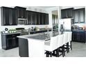 Modern kitchen featuring dark cabinets, stainless steel appliances, and a spacious island with bar seating at 13520 White Sapphire Rd, Riverview, FL 33579