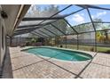 Backyard oasis featuring a screened-in pool and spa, with a brick deck, and partial shade at 15846 Glenarn Dr, Tampa, FL 33618