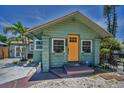 Charming home featuring a yellow door, complemented by flower-filled window boxes and mature landscaping at 1801 52Nd S St, Gulfport, FL 33707