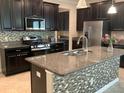 Modern kitchen featuring dark cabinets, granite countertops, stainless steel appliances and an island sink at 2588 Bartolo Dr, Land O Lakes, FL 34639