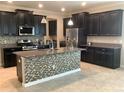 Stylish kitchen with dark cabinets, a granite island with mosaic accents, and stainless steel appliances at 2588 Bartolo Dr, Land O Lakes, FL 34639