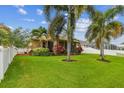 Lush backyard featuring palm trees, manicured landscaping, and a white fence at 27810 Sky Lake Cir, Wesley Chapel, FL 33544