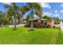 Expansive backyard with a screened-in lanai, mature palm trees, and a white picket fence at 27810 Sky Lake Cir, Wesley Chapel, FL 33544