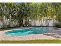 Inviting backyard pool surrounded by lush tropical landscaping, white fencing, and brick pavers at 5107 W Platt St, Tampa, FL 33609